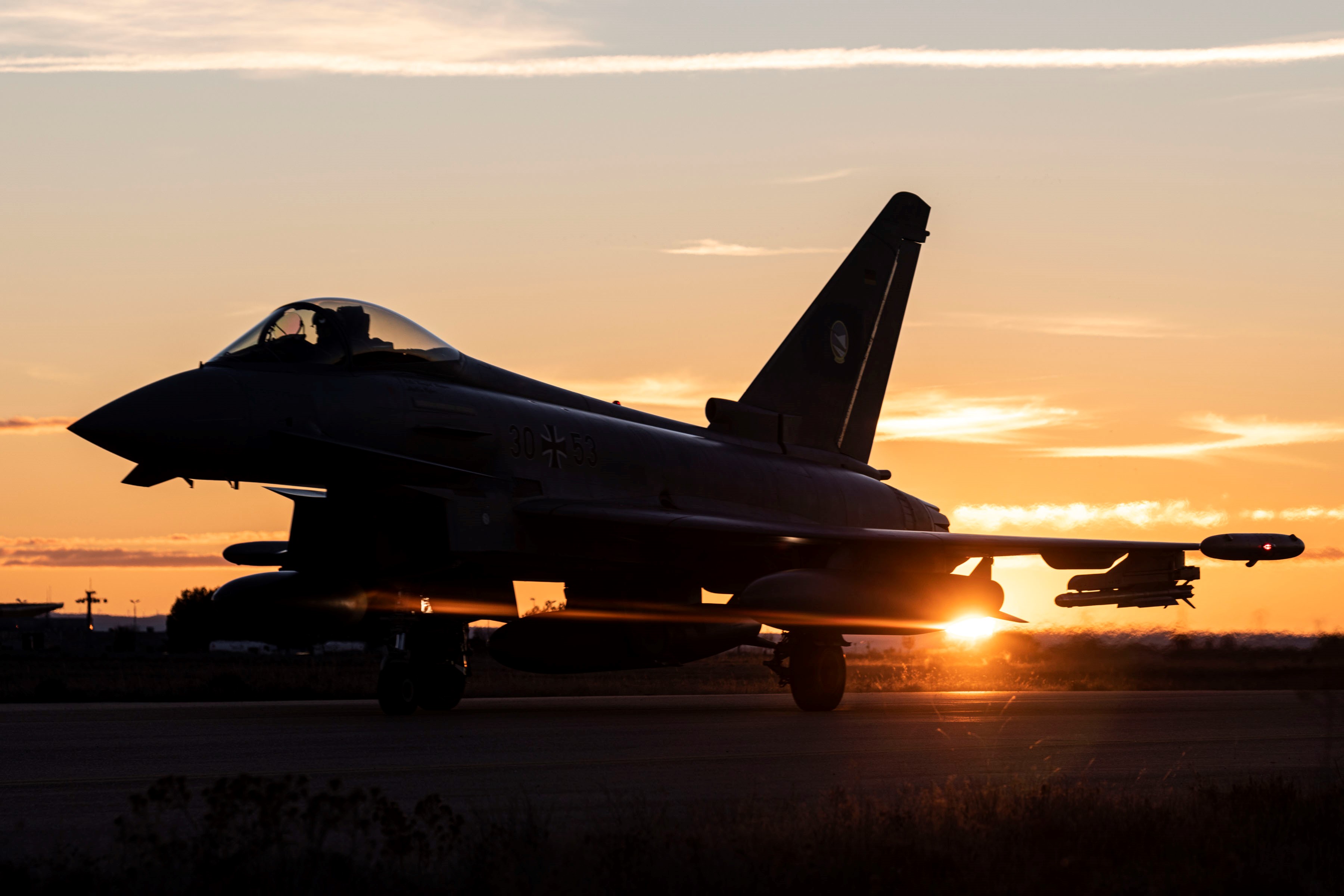 Fighter aircraft on the ground, during sunset.